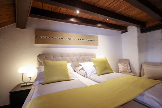 The hotel room at Hotel Auberge Aal Veinen Beim Hunn in Vianden. The rustic room features a hotel bed with a yellow blanket and is thoughtfully decorated.