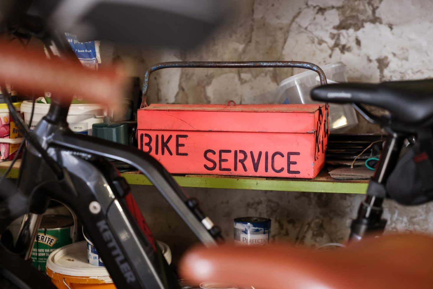 A red toolbox labeled "Bike Service" in a bicycle workshop.