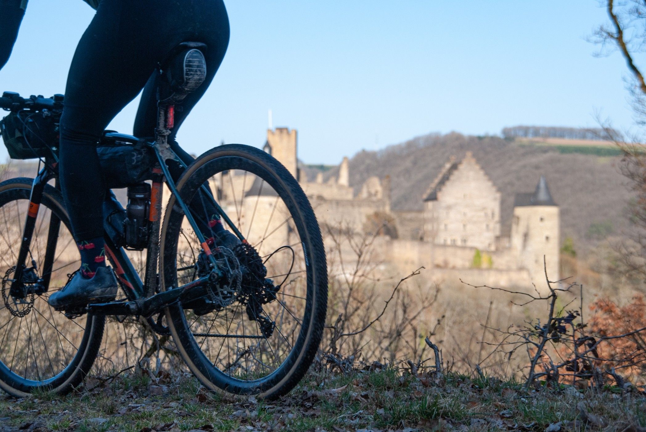 A mountain bike rides past, with Vianden Castle visible in the background.