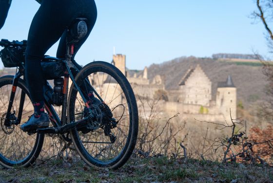 Ein Mountainbike, das gerade vorbeifährt, im Hintergrund ist die Burg Vianden zu sehen.