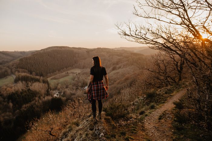 Une femme est debout sur un belvédère en été. Elle regarde au loin et admire la nature qui l'entoure.